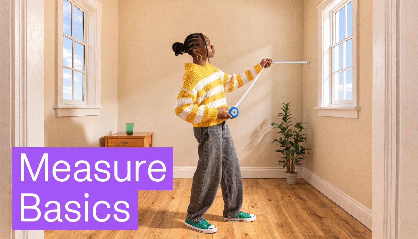 A person in a striped sweater measures the width of a window in an empty room.
