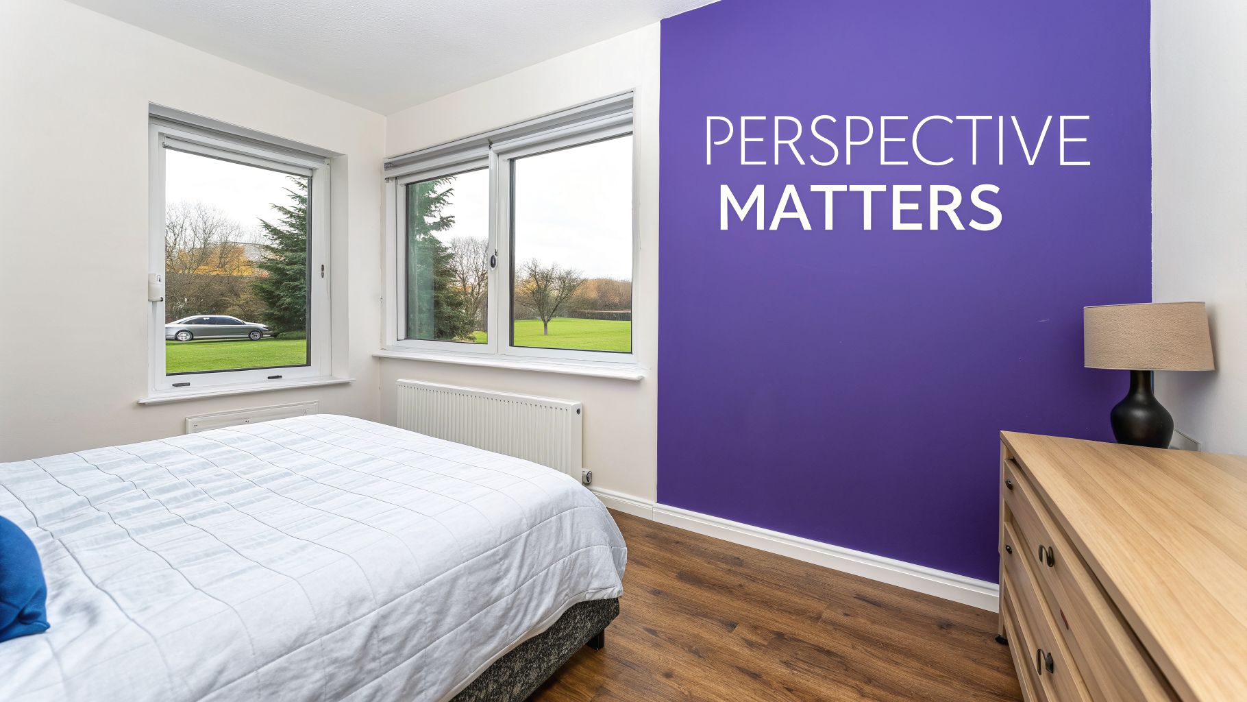A modern bedroom with a bed, purple accent wall featuring text, and windows overlooking a field.