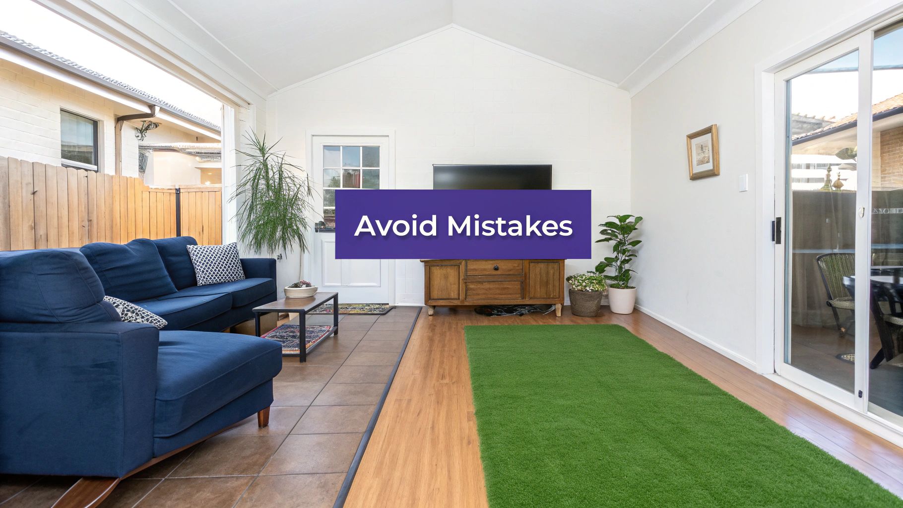 Spacious, sunlit living room with white walls, wooden floor, a purple sofa, and a grey sofa.