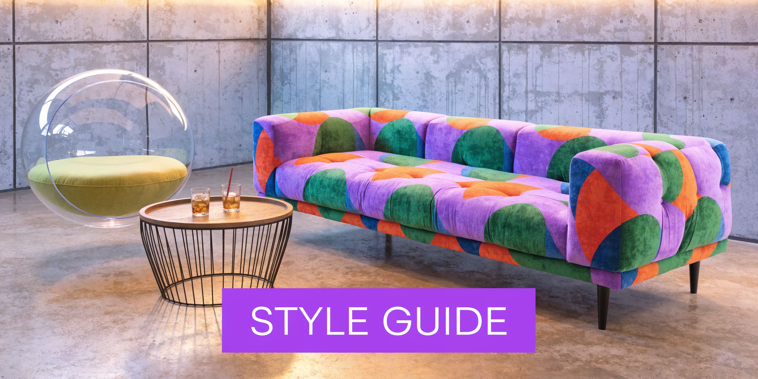 A colorful patterned mid-century modern style sofa next to a bubble chair and circular wooden coffee table.