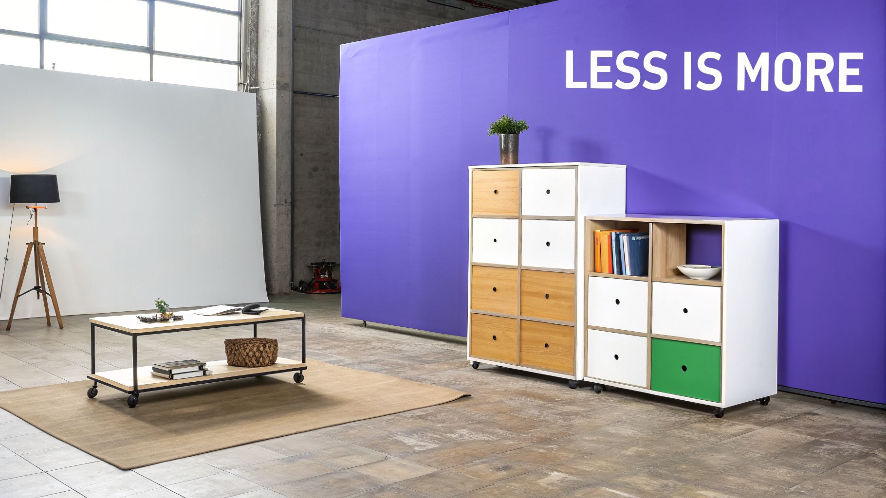 Modern studio interior with modular storage units, a rolling coffee table, and a purple wall.