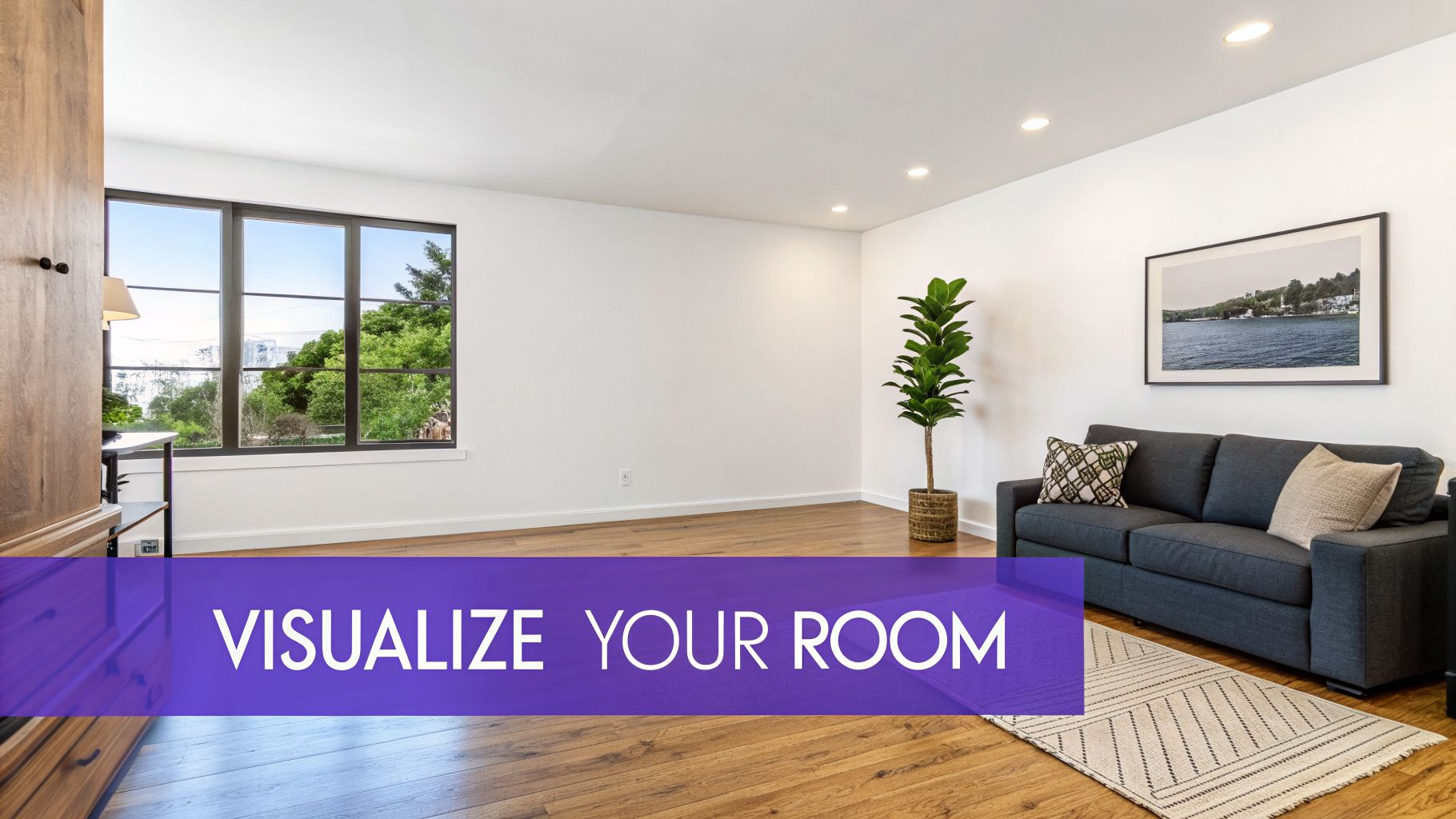 A bright, modern living room featuring a dark gray sofa, large window, potted plant, and wooden floor.